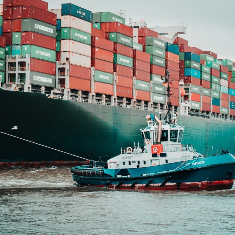 a tug boat pulling a large container ship